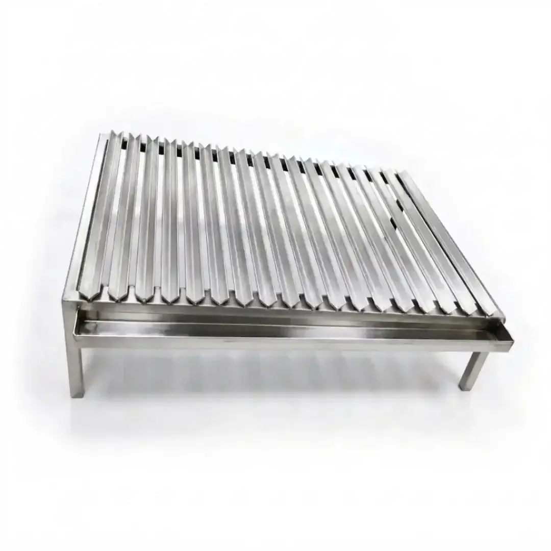 superficie de parrillas en forma de V y acumulador desmontables de acero inoxidable, en un marco rectangular inclinado con patas de acero inoxidable.